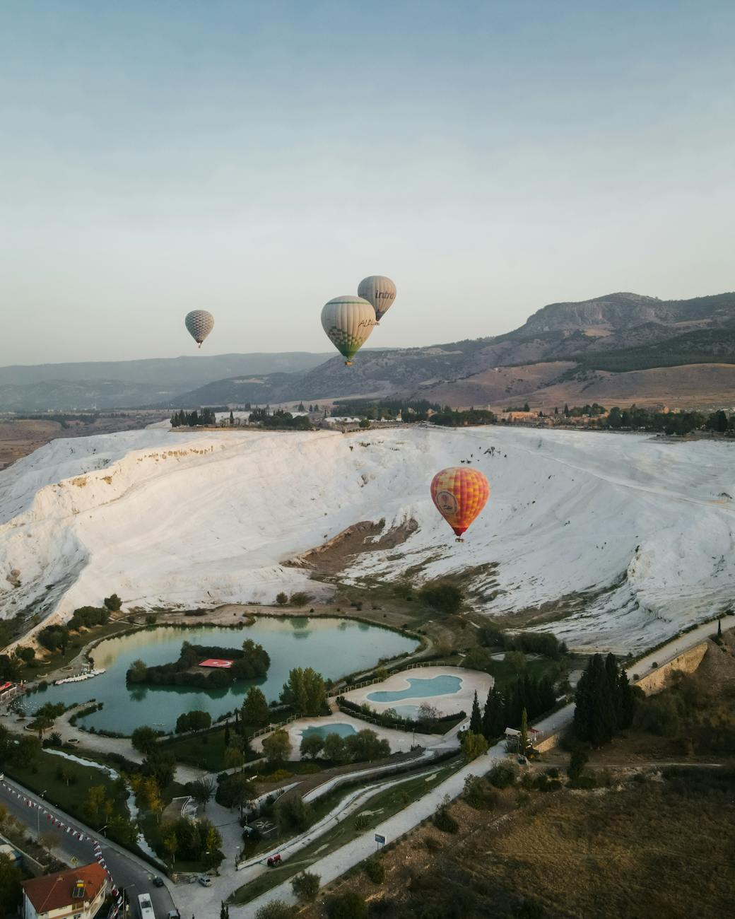 aerial view of hot air baloons over piknik alani park and travertines in pamukkale